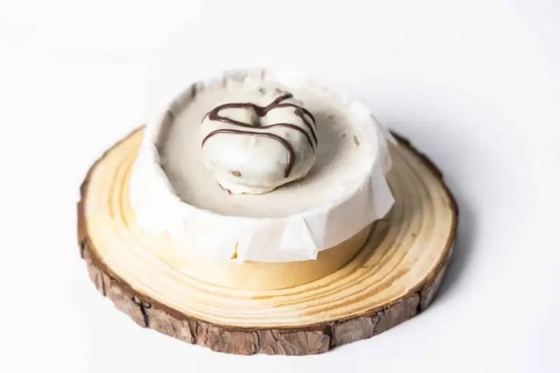 Deliciosa tarta de oro, cubierta de blanco y decorada con chocolate. Presentada sobre una base de madera rústica.