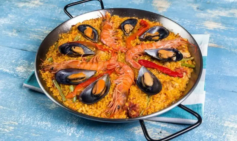 Paella mixta con gambas y mejillones, un festín de sabores mediterráneos en una paellera.