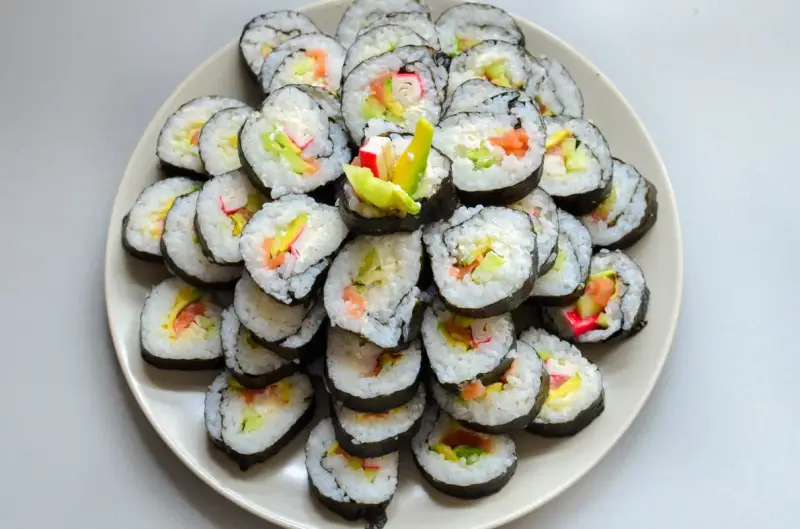 Talerz sushi z paluszkami krabowymi, awokado i łososiem. Idealne do nauki, jak przygotować paluszki krabowe do sushi.