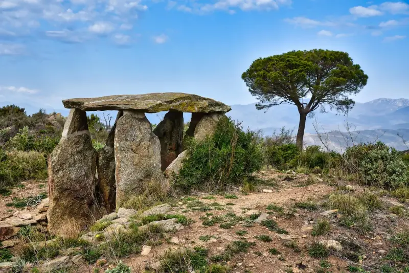Starożytny menhir, kamienna konstrukcja, stoi na wzgórzu pod błękitnym niebem.