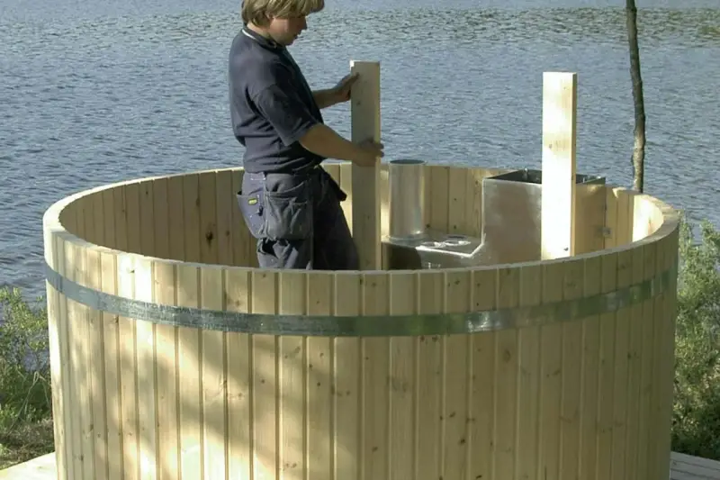 Man bygga badtunna vid sjön. Träet är nytt och redo för montering.