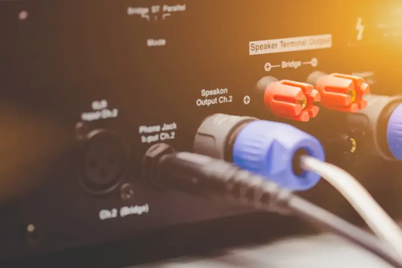 Złącza Speakon i zaciski głośnikowe na wzmacniaczu, pokazujące różne **cable types** do podłączenia sprzętu audio.