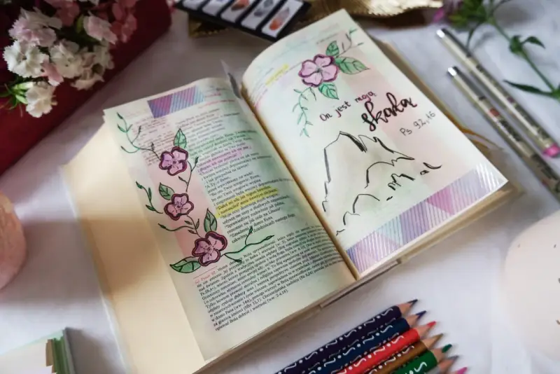 Piękne bible journaling ideas: otwarta Biblia z rysunkami kwiatów i gór, cytat "On jest moją skałą".