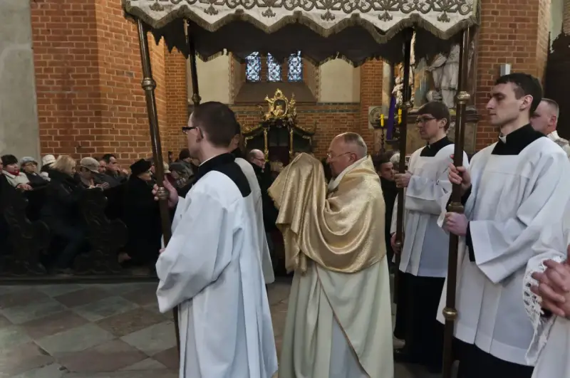 Uroczysta procesja w kościele, kapłan niesie monstrancję okrytą złotym welonem. To symboliczna rezurekcja.