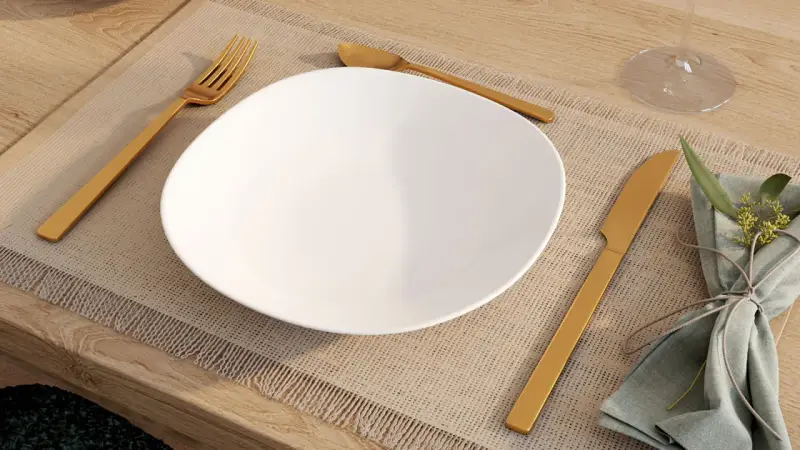 Une assiette blanche est dressée sur un set de table, avec la position des couverts à la française : fourchette à gauche, couteau à droite.