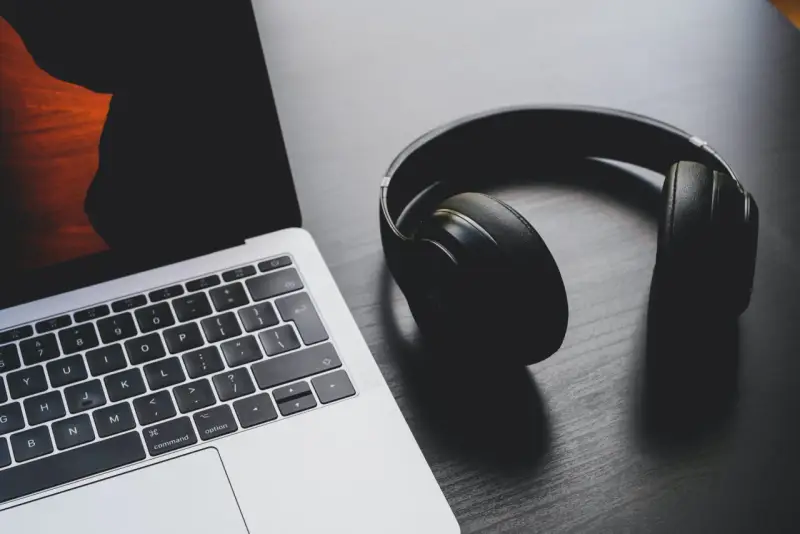 Słuchawki leżą obok laptopa. Może to być sygnał, że występuje brak dźwięku w laptopie i potrzebne są słuchawki do słuchania.