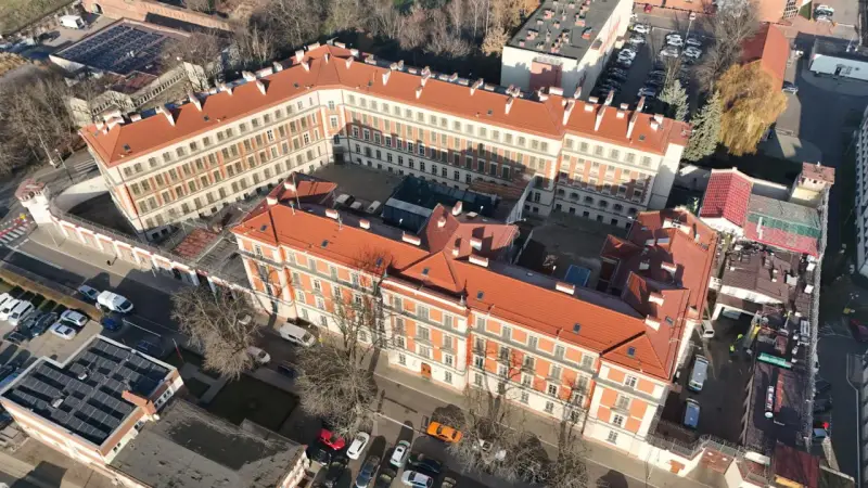 Widok z lotu ptaka na zakład karny Montelupich. Widać budynki z czerwonymi dachami, ogrodzenie z drutem kolczastym i parking. Odwiedziny w zakładzie karnym.