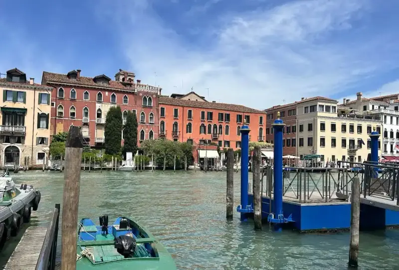 Canale di Venezia con edifici colorati e pontili blu. Per sapere how to get from Venice train station to San Marco, prendi un vaporetto.