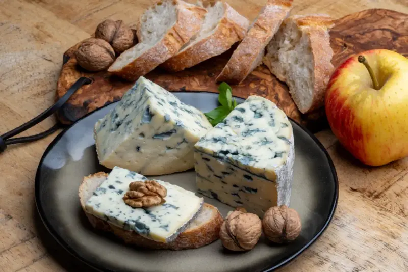 Kawałki sera gorgonzola z niebieską pleśnią, podane z chlebem, orzechami i jabłkiem. Idealne na przekąskę, która odpowie na pytanie: co to gorgonzola.