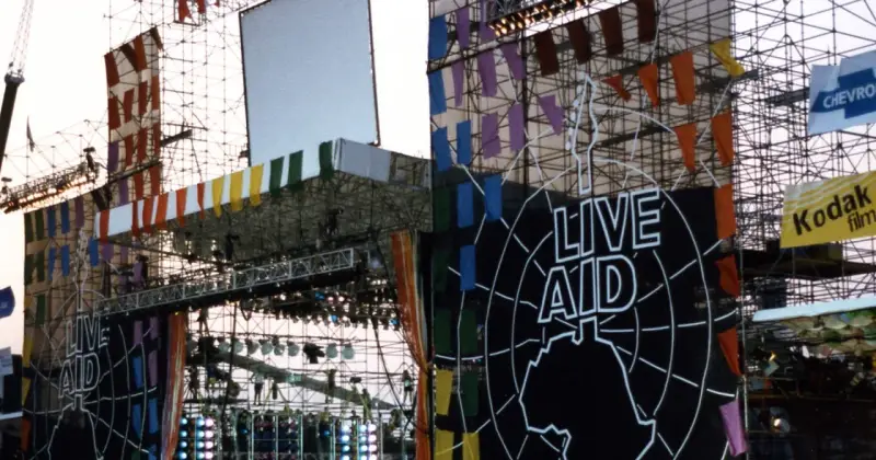 Scena Live Aid w Polsce, ozdobiona kolorowymi flagami i wielkim logo.