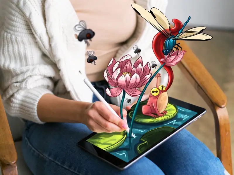 Osoba rysuje na tablecie za pomocą programu do rysowania na komputerze. Na ekranie pojawia się żaba, ważka i kwiat lotosu.