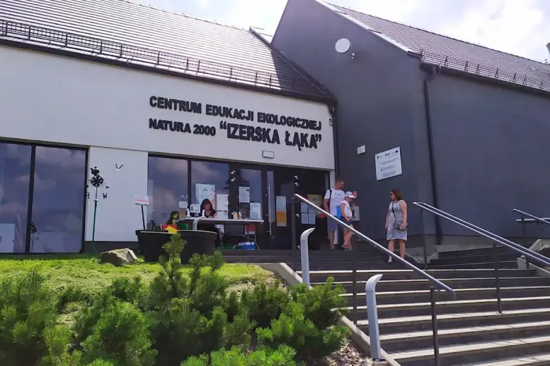 Centrum Edukacji Ekologicznej Natura 2000 "Izerska Łąka" zaprasza. Rodzina wchodzi po schodach do budynku.