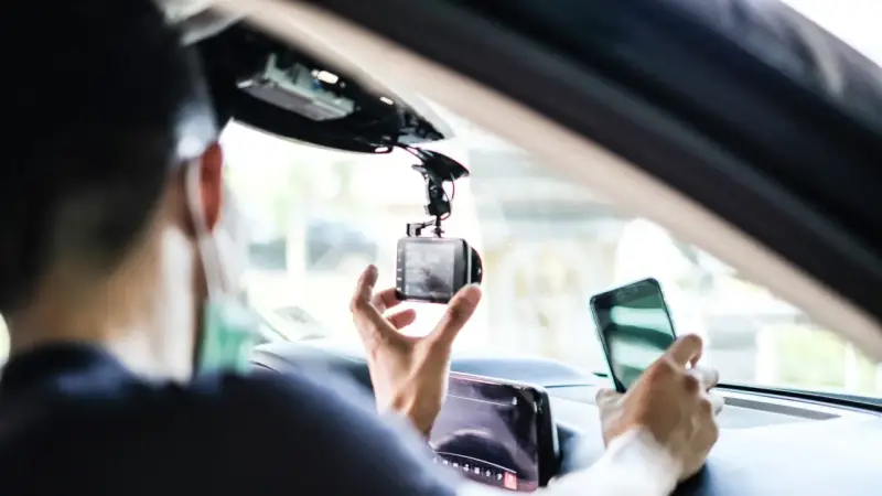 Mann installiert Dashcam im Auto, ADAC-Mitglieder profitieren von sicherer Fahrt.