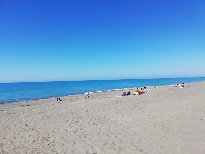 Słoneczny dzień na plaży w Marina di Bibbona. Ludzie odpoczywają na piasku, a morze lśni w słońcu.
