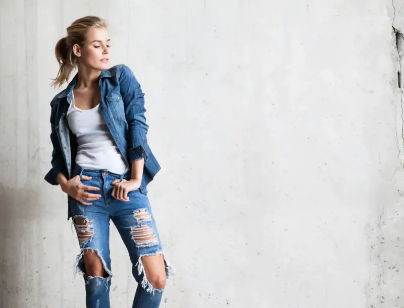 Stylowa blondynka w rozdartych jeansach i jeansowej koszuli. Inspiracja, jak nosić koszulę do jeansów.