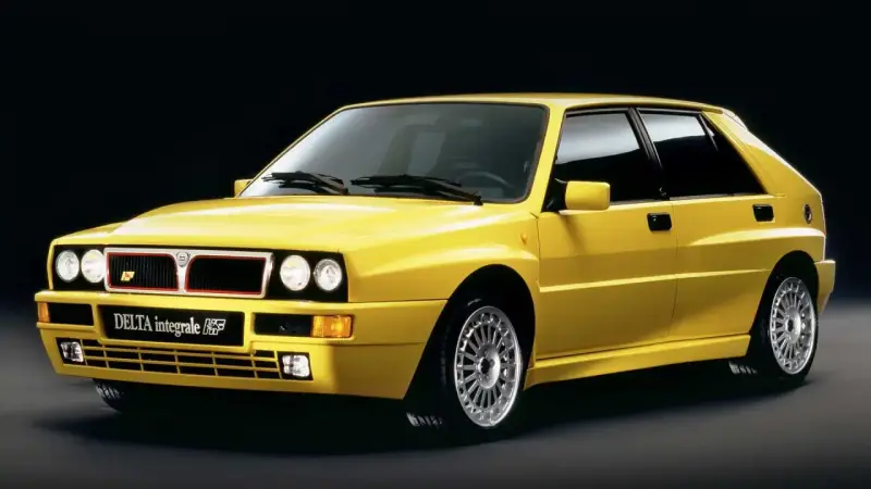 Żółta Lancia Delta Integrale HF z lat 90. na czarnym tle, z charakterystycznym grillem i felgami.