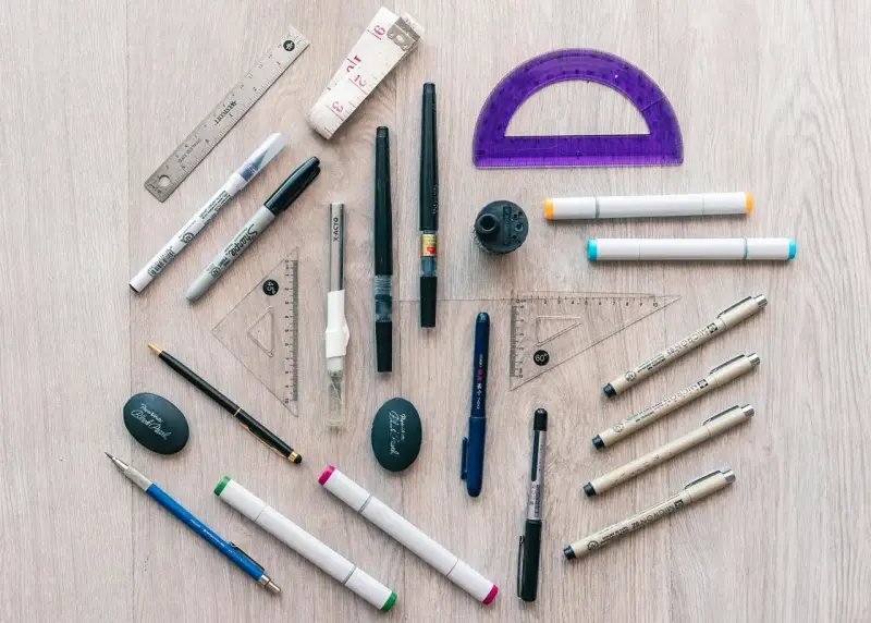 Herramientas de dibujo: reglas, escuadras, transportador, marcadores, bolígrafos y un sacapuntas. ¡Todo listo para crear!