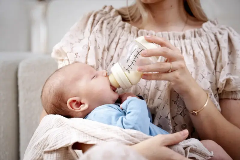 Mama karmi maluszka z butelki, która może być najlepszą butelką antykolkową dla noworodka.
