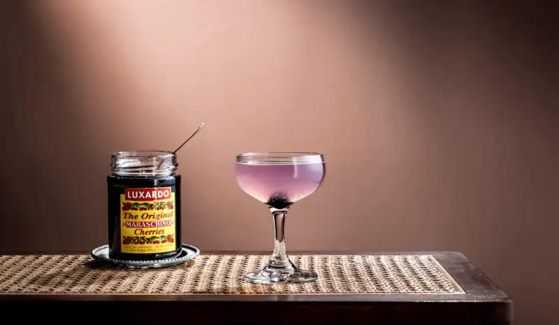 En elegant aviation drink med en burk Luxardo maraschino-körsbär, redo att förhöja smaken.