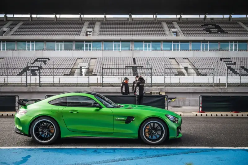 Zielony Mercedes GTR na torze wyścigowym, gotowy do jazdy. Za nim puste trybuny stadionu.