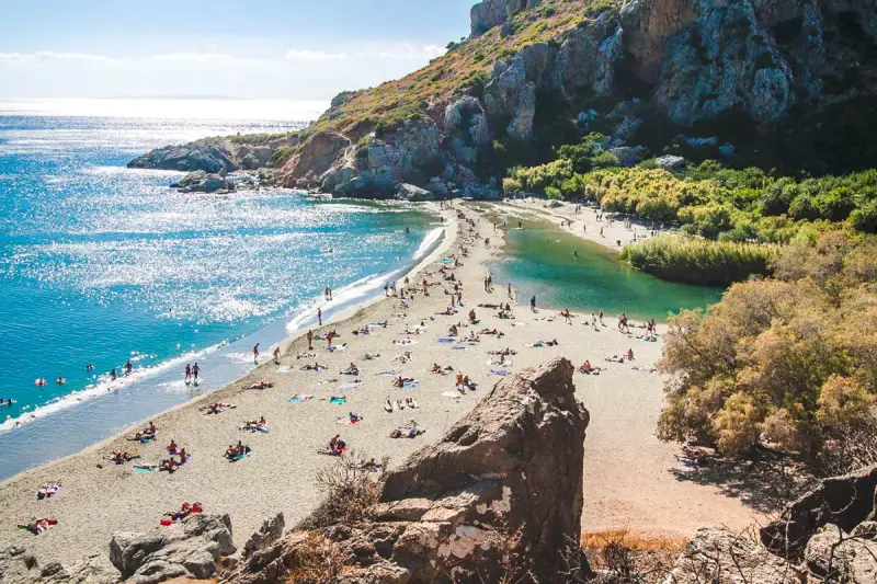 Słoneczny dzień na plaży Preveli. Ludzie odpoczywają na piasku, kąpiel w turkusowej wodzie laguny i morza.