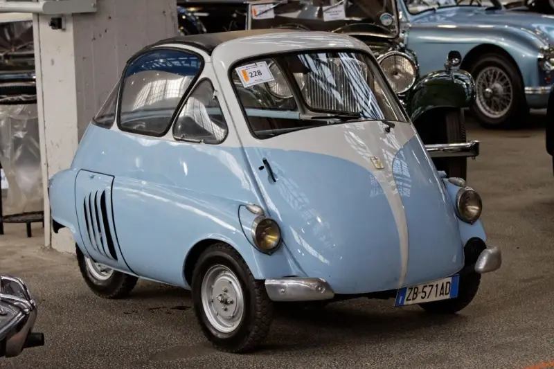 Urocze, błękitno-białe BMW Isetta z lat 50. z charakterystycznymi drzwiami z przodu, gotowe na przejażdżkę po mieście.