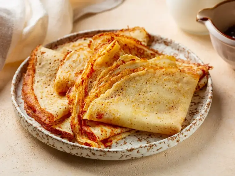 Stos gotowych naleśników na talerzu, idealnych jako składniki na naleśniki do dalszego przygotowania.