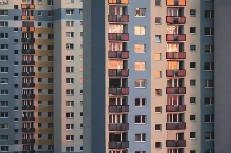 Widok na fasadę wielopiętrowych bloków mieszkalnych z balkonami i oknami.