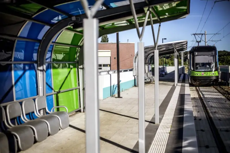 Nowoczesny przystanek tramwajowy w Szczecinie. Zielony tramwaj czeka na pasażerów. Jak dojechać do centrum?