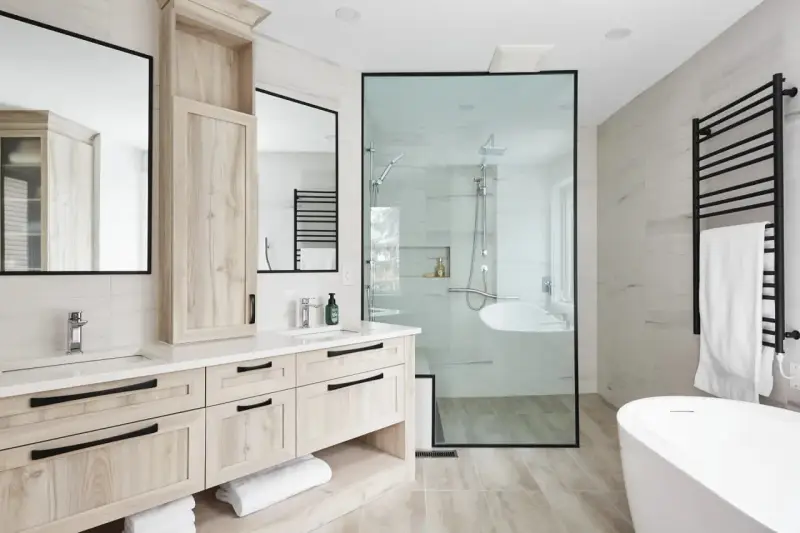 Salle de bain moderne avec double vasque en bois clair, douche vitrée et baignoire îlot. Un design épuré pour une ambiance zen.