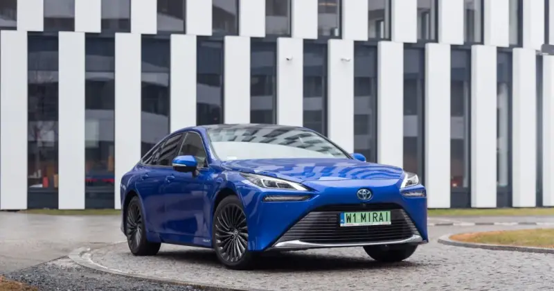Niebieski samochód Toyota Mirai na tle nowoczesnego budynku.