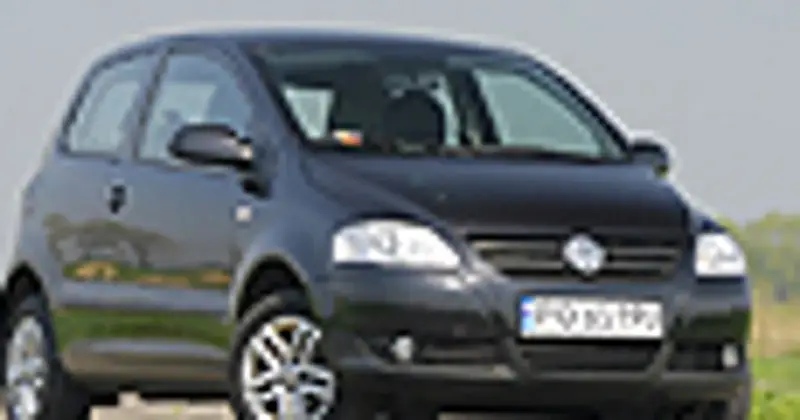 Czarny VW Fox z polskimi tablicami rejestracyjnymi stoi na tle zieleni.