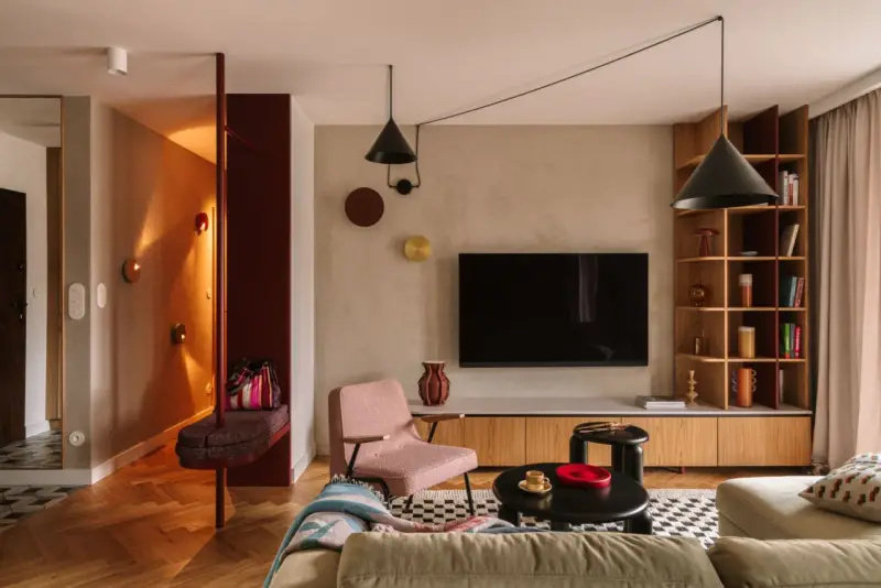 Nowoczesny salon z elementami boho. Wygodna kanapa, różowy fotel, czarne stoliki i regał. W przedpokoju ławka i lustro. Idealne miejsce na relaks po całym dniu. Ten **kosztorys remontu** był wart każdej złotówki.