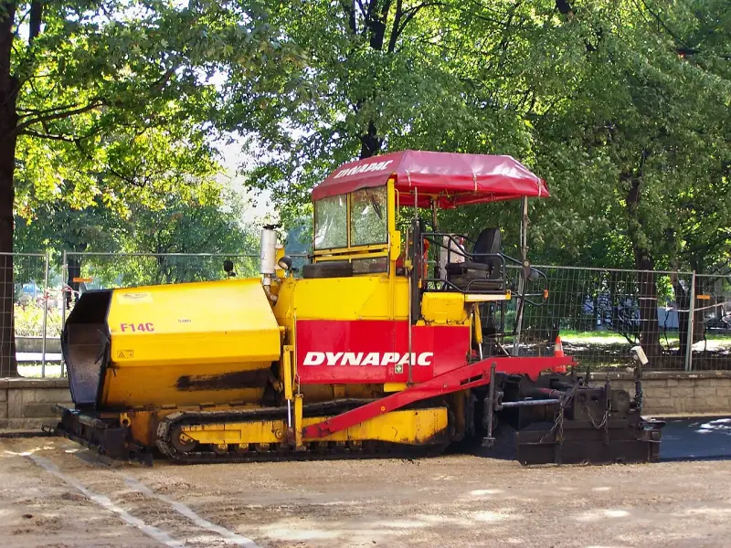 Żółto-czerwony rozściełacz do kruszywa Dynapac F14C na placu budowy.