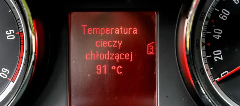 Wyświetlacz pokazuje temperaturę płynu chłodniczego: 91°C. Obok widać fragmenty wskaźników.