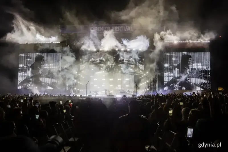 Koncert Linkin Park na Opener Festival. Tłum ludzi z telefonami, dym i światła na scenie.