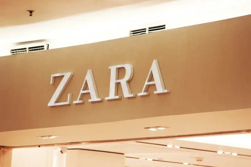 ZARA, znana marka odzieżowa, prezentuje swoje logo na jasnobrązowej ścianie.