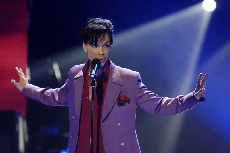 Prince w fioletowej marynarce śpiewa na scenie. Jego śmierć była szokiem dla fanów.