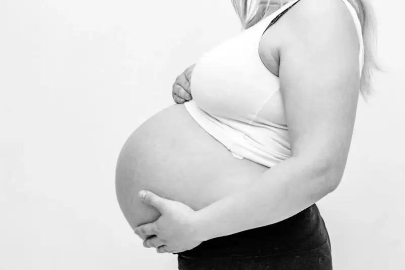 Gravid mage med händer som stöttar. Kanske ont i ljumsken gravid?