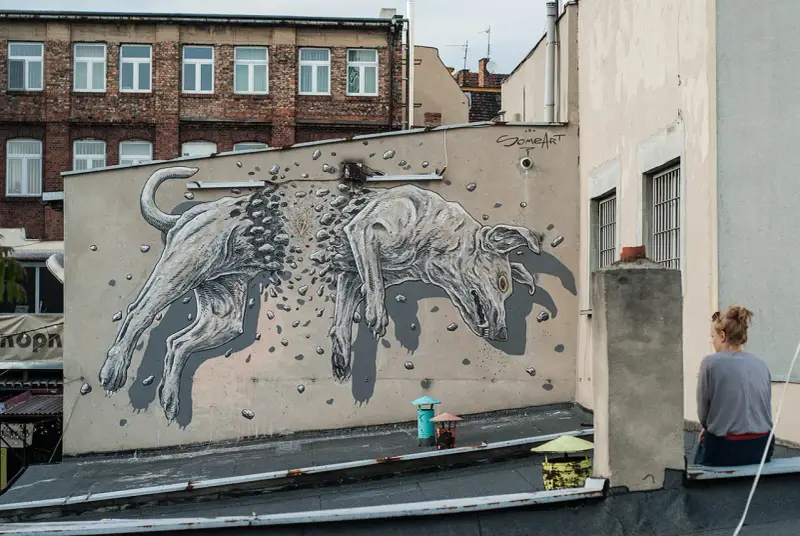 Niesamowite street art graffiti przedstawiające psa rozpadającego się na kamienie. Dzieło sztuki miejskiej na ścianie kamienicy.