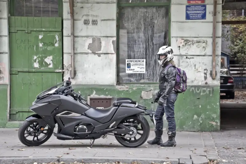 Motocyklista w kasku obok swojego futurystycznego Honda NM4 Vultus.