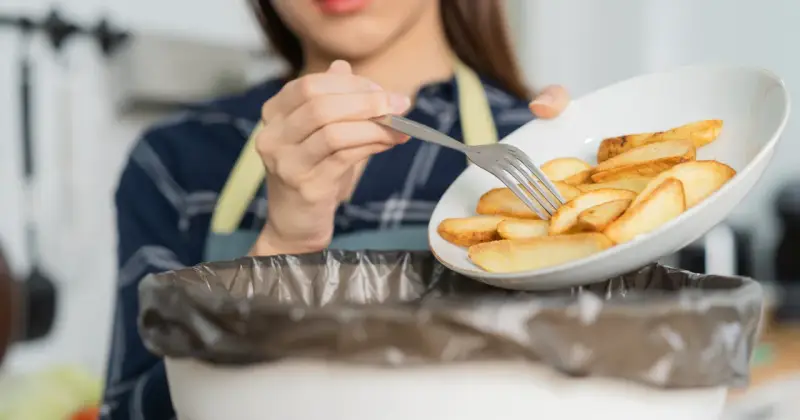 Kobieta wyrzuca frytki, zaczynając drogę do tego, jak obniżyć cholesterol bez leków. Zdrowa dieta to klucz.