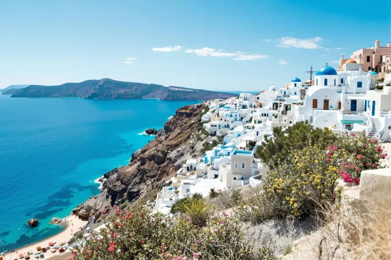 Vue panoramique de Santorin, Grèce, avec des maisons blanches et des dômes bleus surplombant la mer Égée.