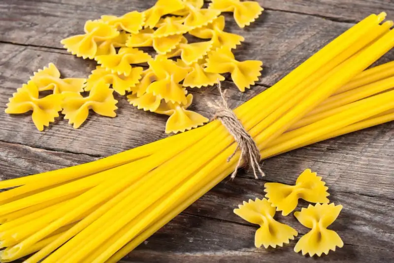 Makaron z mąki durum i zwykłej pszennej. Farfalle i spaghetti na drewnianym tle.