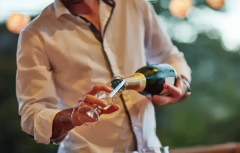 Un hombre sirve cava español en una copa.