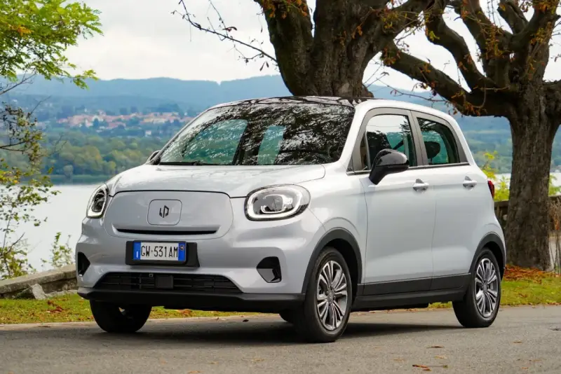Leapmotor T03, un'auto elettrica grigia parcheggiata vicino a un lago, pronta per un viaggio con la sua eccellente autonomia.