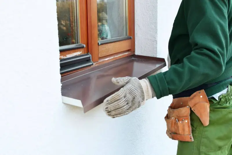Instalación de un vierteaguas metálico en una ventana. El vierteaguas protege la pared de la lluvia.