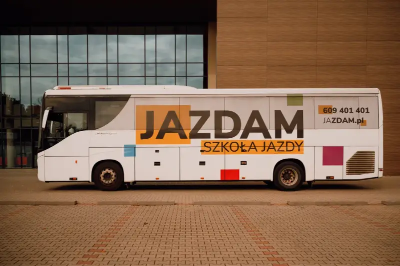 Biały autobus szkolny z napisem "JAZDAM SZKOŁA JAZDY" i numerem telefonu. Idealny do nauki jazdy kategorii D.