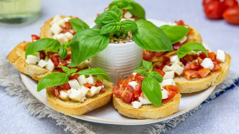 Bruschetta z pomidorami i mozzarellą – pyszny przepis na letnią przekąskę. Chrupiące grzanki z dodatkiem świeżej bazylii.