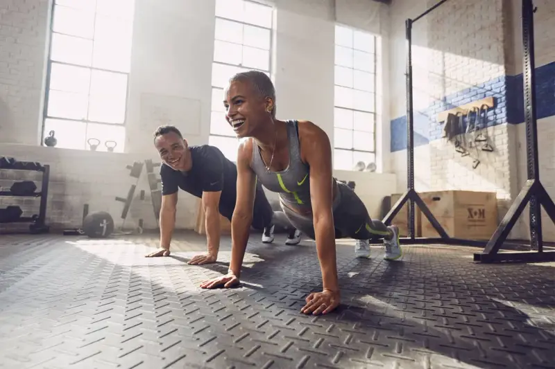 Coppia sorridente in palestra, che fa flessioni. Lo sport è un valido alleato contro la depressione, un modo per ritrovare energia e benessere.